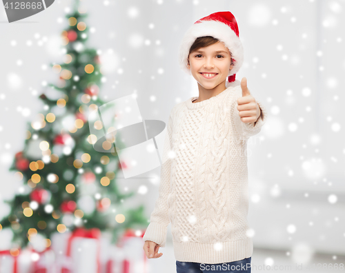 Image of smiling happy boy in santa hat showing thumbs up