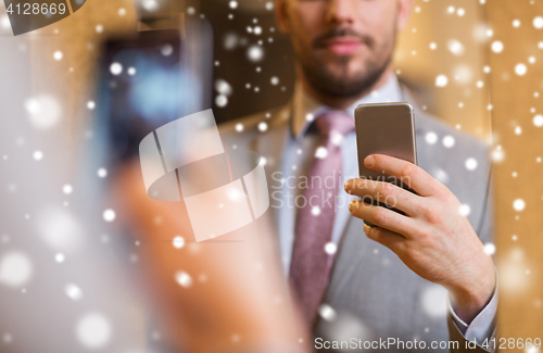 Image of close up of man in suit taking mirror selfie