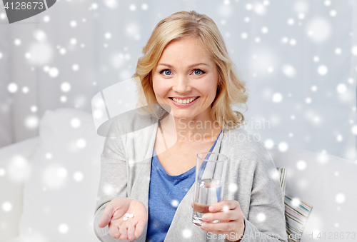 Image of happy woman with medicine and water glass at home