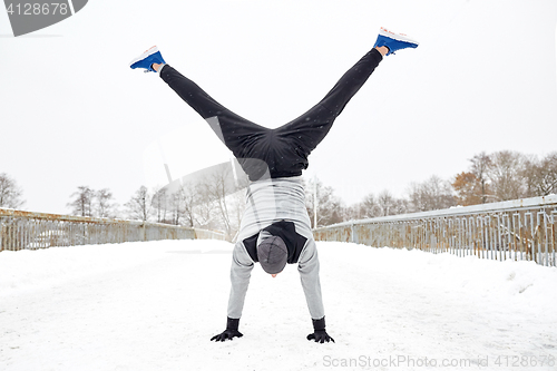 Image of young man doing handstand in winter