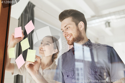 Image of happy creative team writing on stickers at office