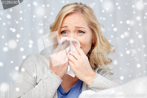 Image of ill woman blowing nose to paper napkin