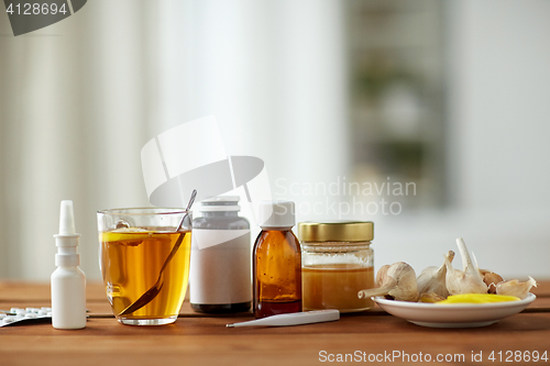 Image of drugs, thermometer, honey and cup of tea on wood