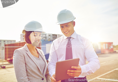 Image of happy builders in hardhats with tablet pc outdoors