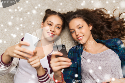 Image of happy teenage girls lying on floor with smartphone