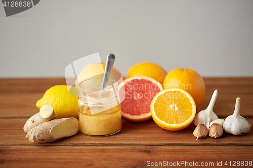 Image of honey, citrus fruits, ginger and garlic on wood