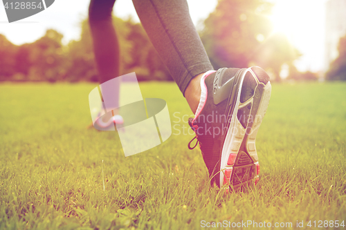 Image of close up of exercising woman legs on grass in park