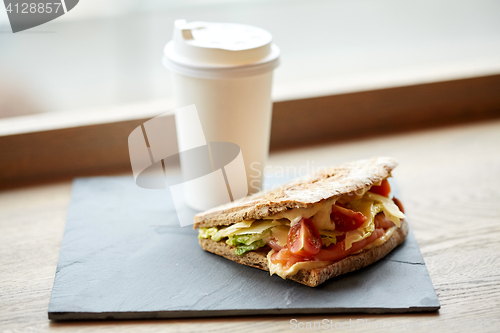 Image of salmon panini sandwich and cup of drink at cafe