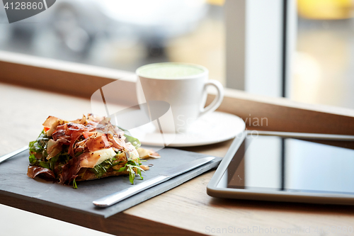 Image of prosciutto ham salad with tablet pc at restaurant