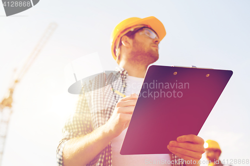 Image of builder in hardhat with clipboard outdoors