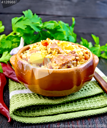 Image of Rice with chicken and zucchini in clay bowl on board