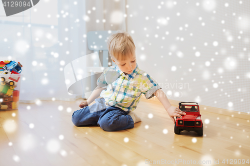 Image of little baby boy playing with toy car at home