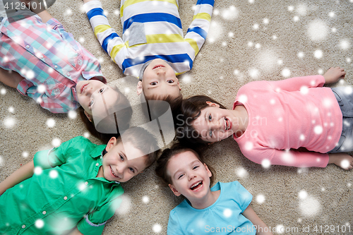 Image of happy smiling children lying on floor over snow