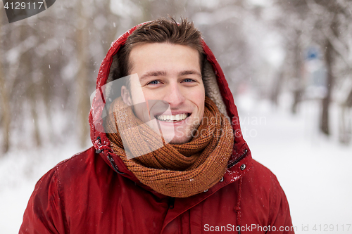 Image of happy man in winter jacket with hood outdoors