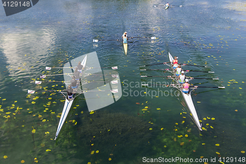 Image of Young athletes rowing on the tranquil lake