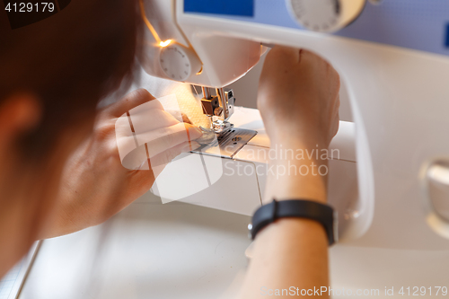 Image of Girl sews fabric on machine