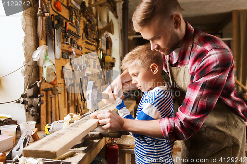 Image of father and son with hammer working at workshop