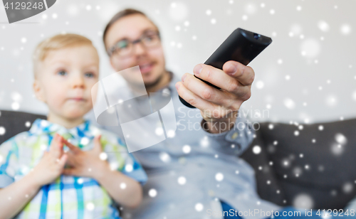 Image of father and son with remote watching tv at home