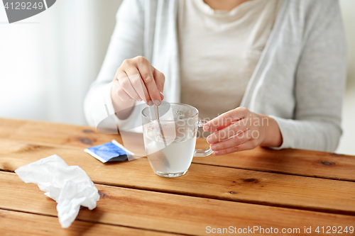 Image of woman stirring medication in cup with spoon