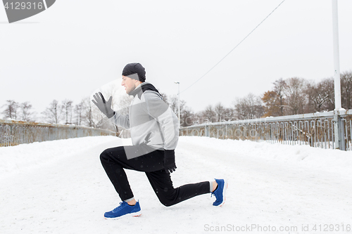 Image of man exercising and doing squats on winter bridge