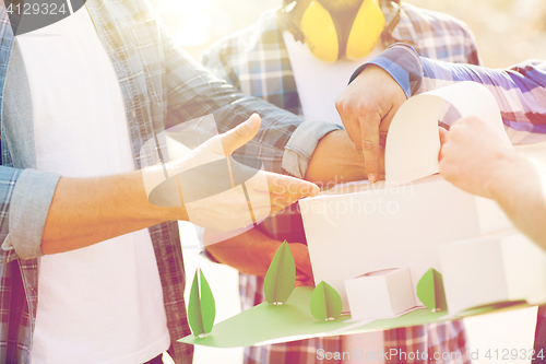 Image of close up of builders with paper house model