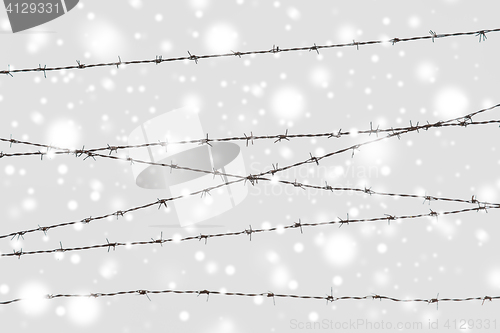 Image of barb wire fence over gray sky and snow