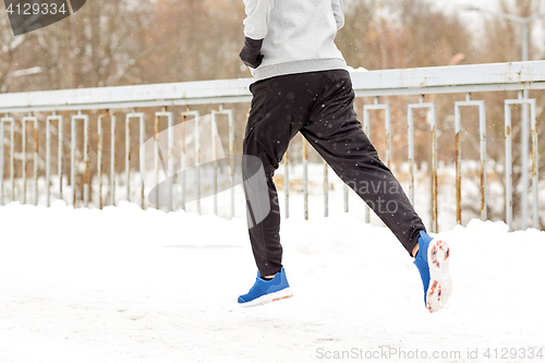 Image of man running along snow covered winter bridge road