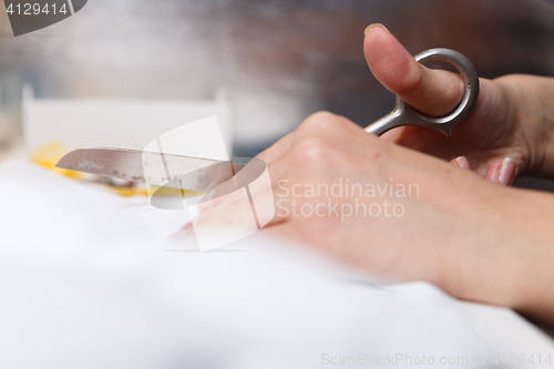 Image of Girl with scissors cuts fabric