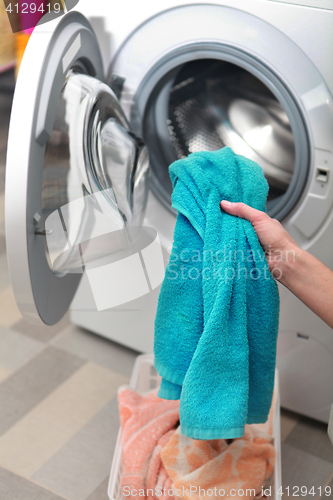 Image of woman loading clothes in washing machine