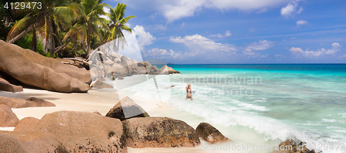 Image of Woman enjoying Anse Patates picture perfect beach on La Digue Island, Seychelles.