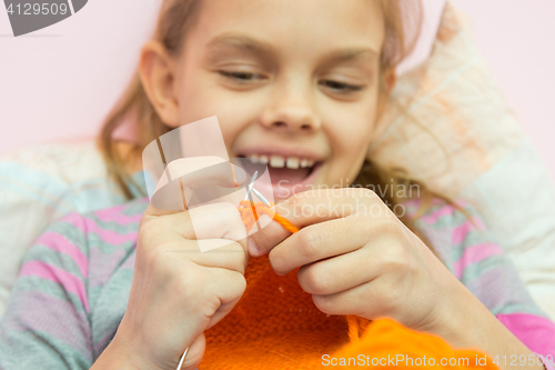 Image of Happy girl knits on the needles, close-up, focus on the spokes