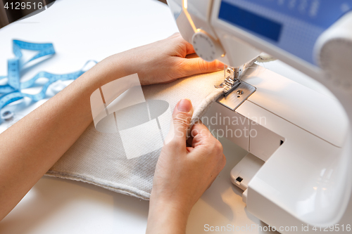 Image of Woman sews fabric on machine