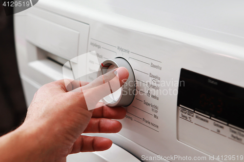Image of man's hand adjusting washing machine