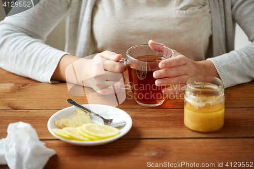 Image of close up of woman adding lemon to tea cup