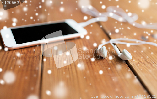Image of close up of blank smartphone and earphones on wood