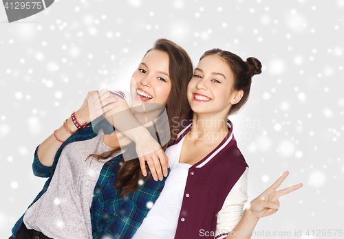 Image of happy teenage girls hugging and showing peace sign