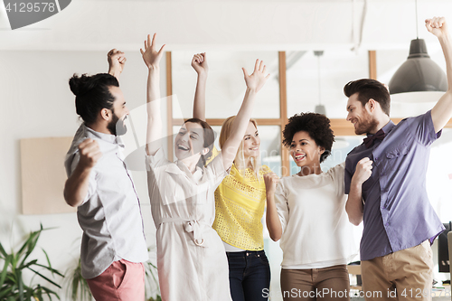 Image of happy creative team celebrating victory in office