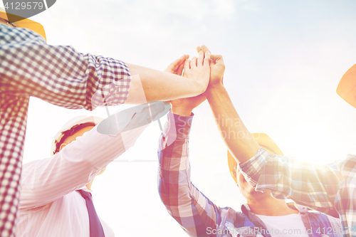 Image of close up of builders in hardhats making high five