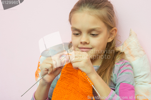 Image of The girl knits on the needles orange scarf