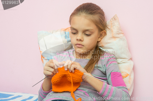 Image of The girl knits on spokes sitting on the bed