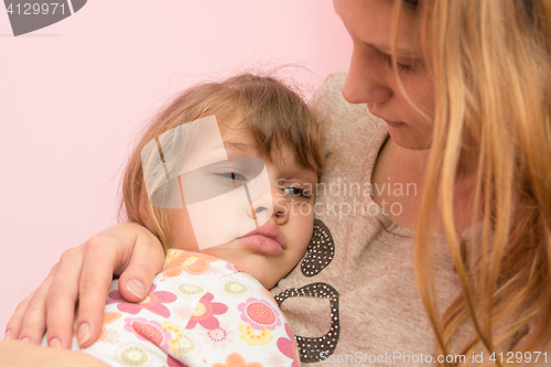 Image of Sad five year old girl clung to her mother