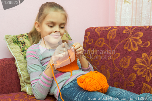 Image of Girl lying on the couch and knits on spokes