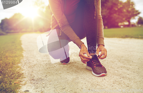 Image of close up of woman tying shoelaces outdoors