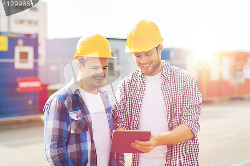 Image of smiling builders in hardhats with tablet pc