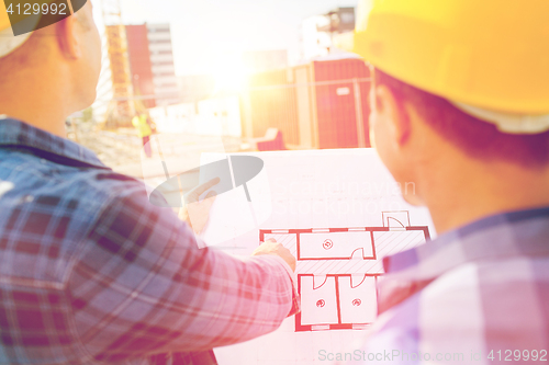 Image of close up of builders with blueprint at building