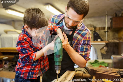 Image of father and son with drill working at workshop