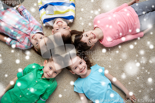 Image of happy smiling children lying on floor over snow