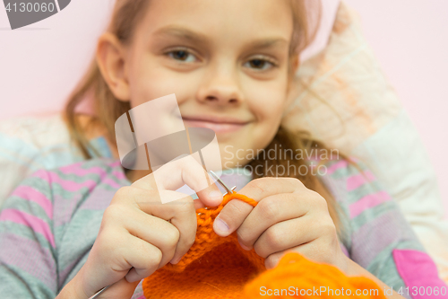 Image of Happy girl knits on the needles, and looked into the frame, the camera focuses on the spokes