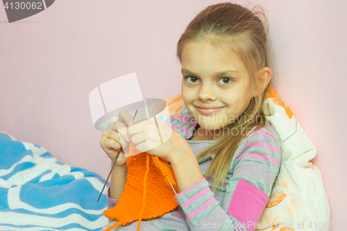 Image of The girl knits on the needles, and looked into the frame