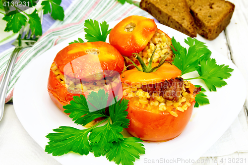 Image of Tomatoes stuffed with bulgur and parsley in plate on light boar